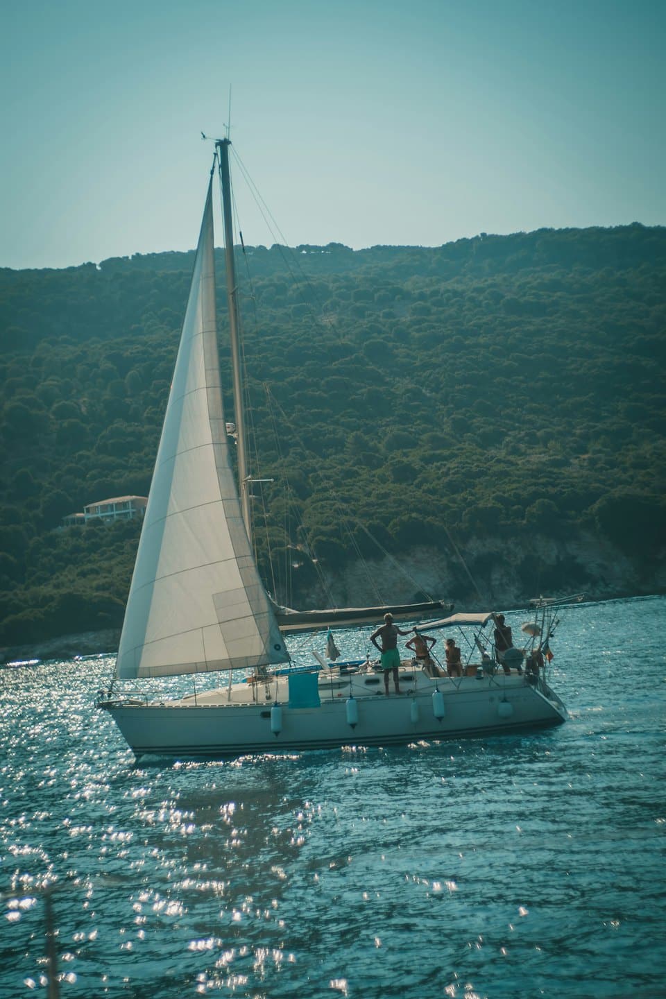 Menschen segeln auf einem weißen Boot über das Wasser.